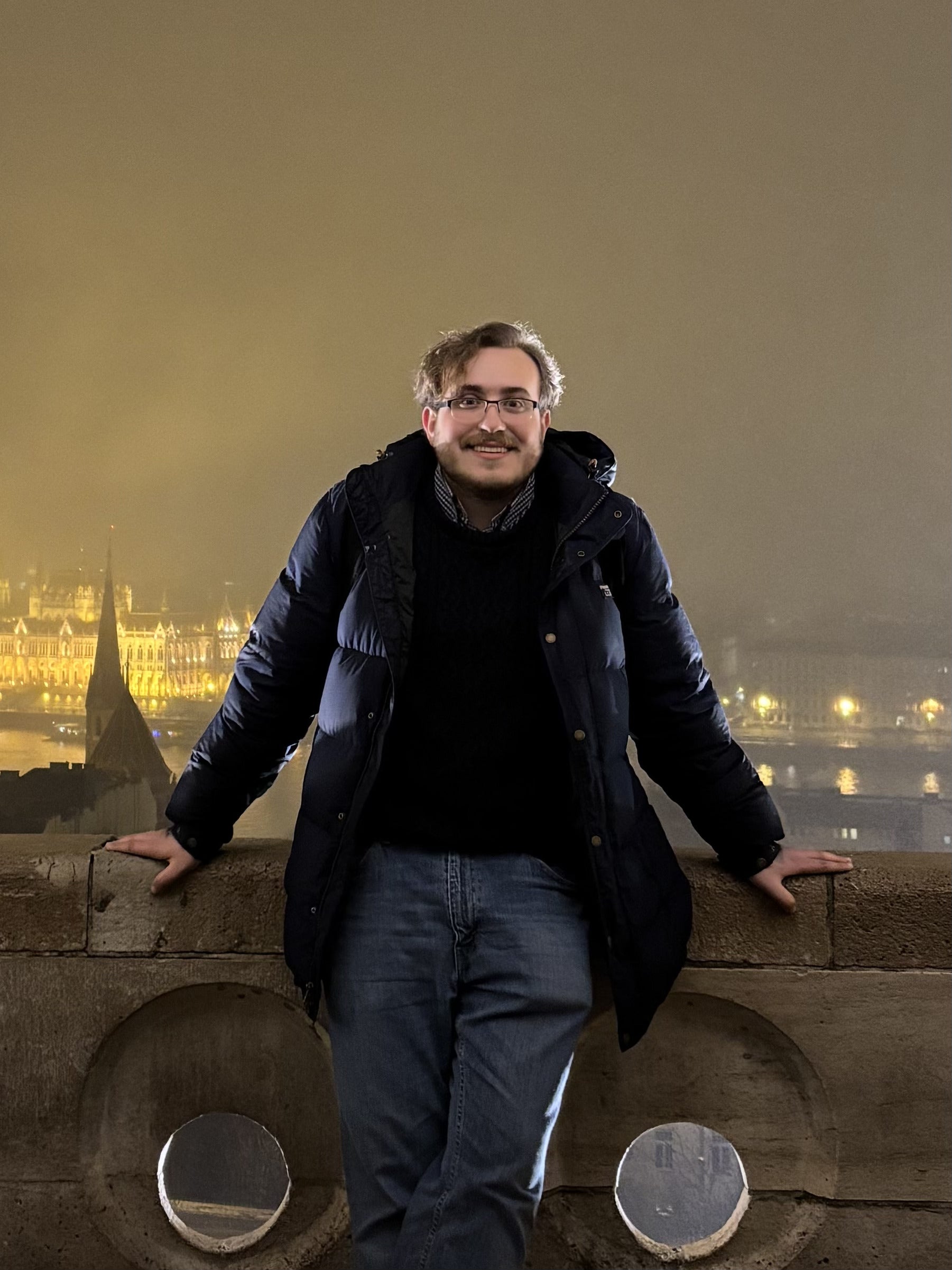 Charles, a RARE Center research associate standing outdoors at night overlooking a cityscape and illuminated historic buildings.