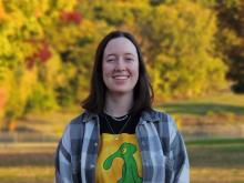 Sam, a PhD Candidate at the RARE Center, smiling in front of a beautiful outdoor scene. 