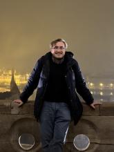 Charles, a RARE Center research associate standing outdoors at night overlooking a cityscape and illuminated historic buildings.